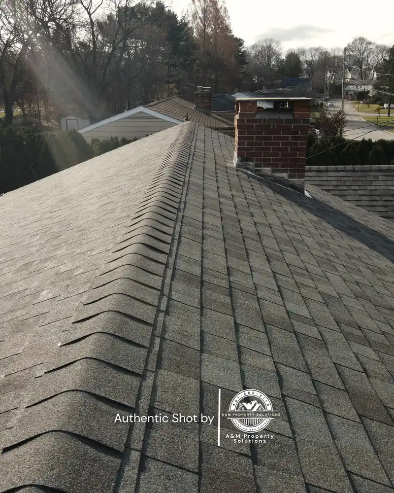 Aerial view along the ridge line of a newly completed asphalt shingle roof.